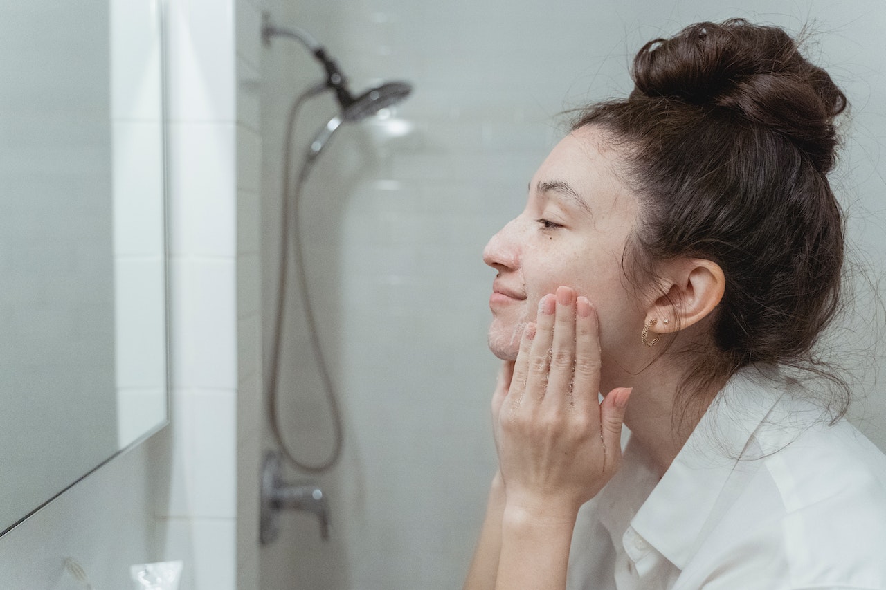 A young woman washes her face with a soap-free cleanser