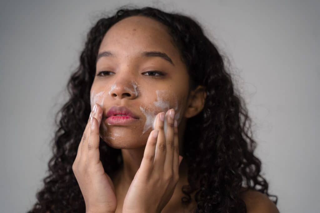 Young girl washing face with facial foam